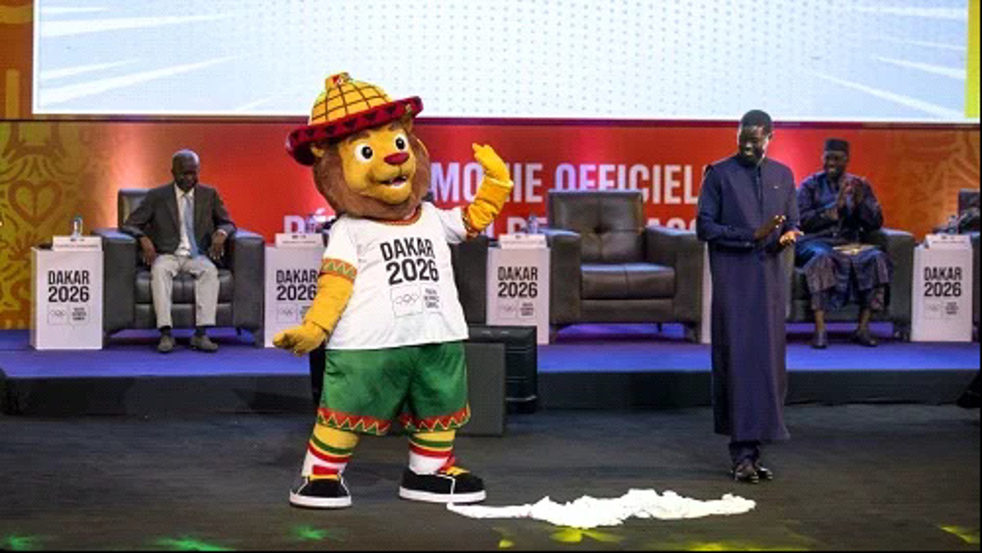 Ayo, la mascotte des JOJ de Dakar 2026 arbore la crinière de l'Afrique et est coiffé du Tingandé, le chapeau traditionnel peul. Avec un djembé à la main, il dit combien l'art d'accueillir est autant une valeur qu'une fête au Sénégal.